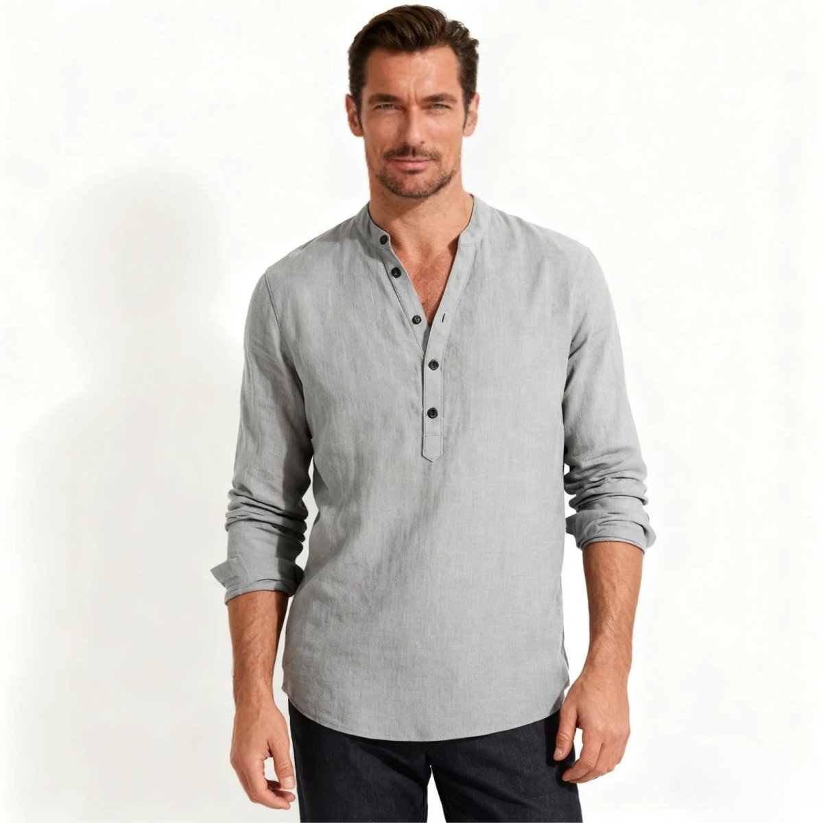 Male model wearing the Kouvr Fashion light grey linen blend band collar henley shirt with long sleeves, paired with dark trousers.