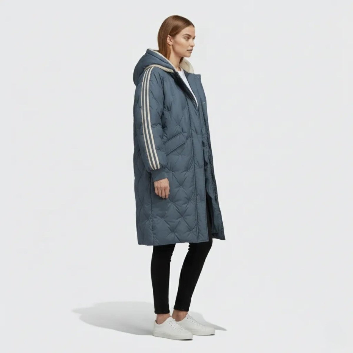 Side profile of a woman in the Kouvr Fashion Meridian slate dark blue parka, showing the knee-length cut and stripe detail on the sleeve.