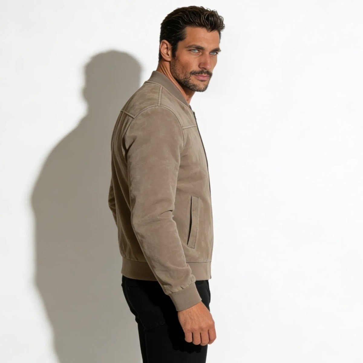 Side profile of a man wearing the Kouvr Fashion taupe suede bomber jacket, showcasing the fit and sleeve details.
