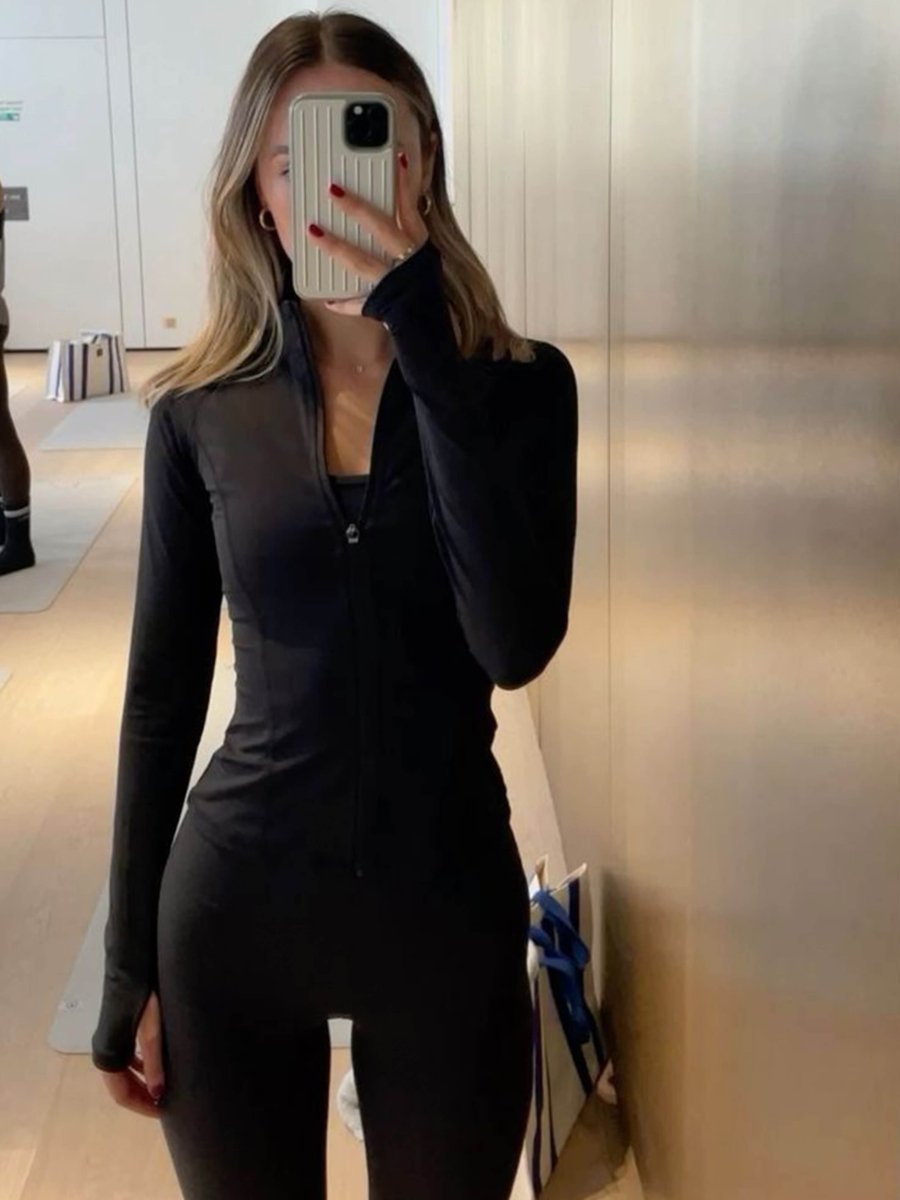 Woman wearing a black headband and the black Kouvr Nola Sculpt Jacket, showing a full workout outfit in a bedroom mirror selfie.