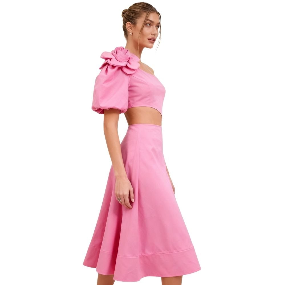 Model wearing Kouvr's pink one-shoulder midi dress with a large rose on the shoulder and a side waist cutout