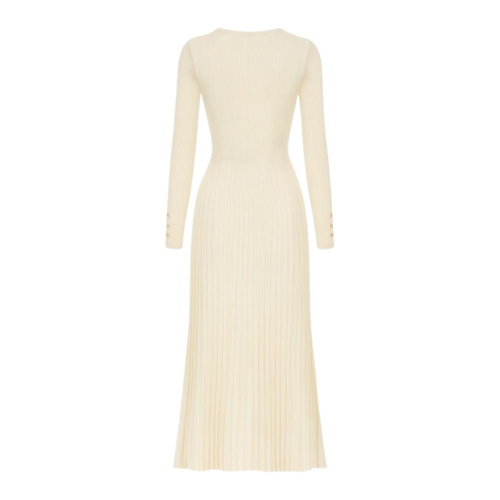 Model wearing the Kouvr Fashion long sleeve pleated knit maxi dress in cream, posing in a minimalist room