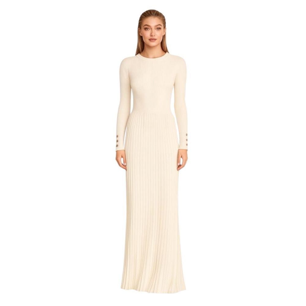 Model wearing the Kouvr Fashion long sleeve pleated knit maxi dress in cream, posing in a minimalist room
