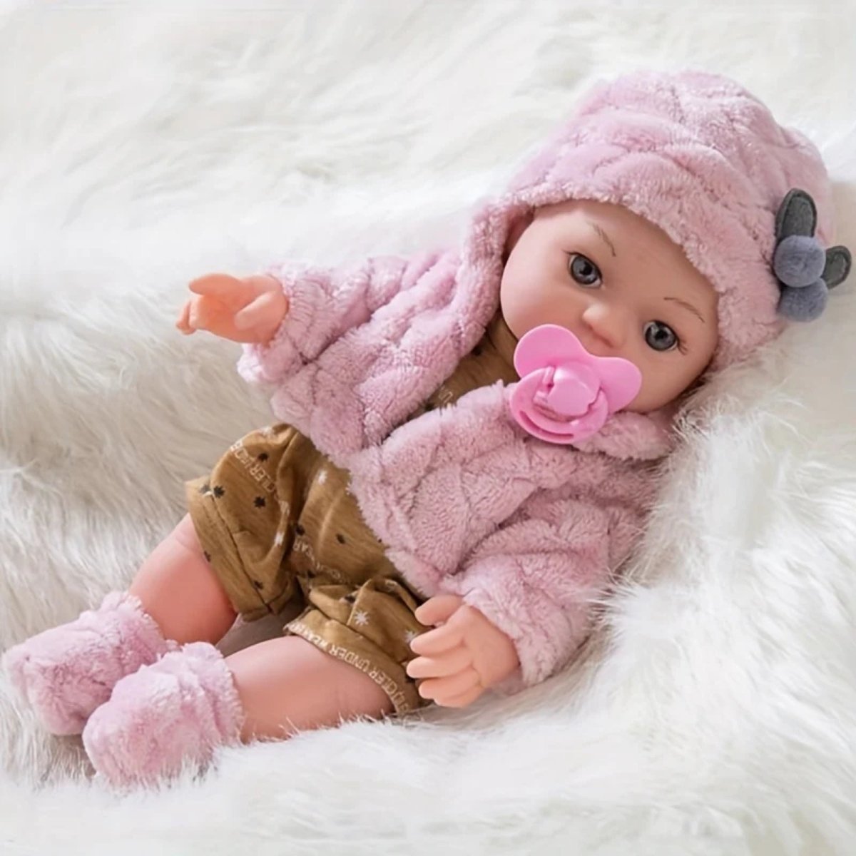 Kouvr Baby doll in pink outfit and hat with pacifier on a white fluffy surface