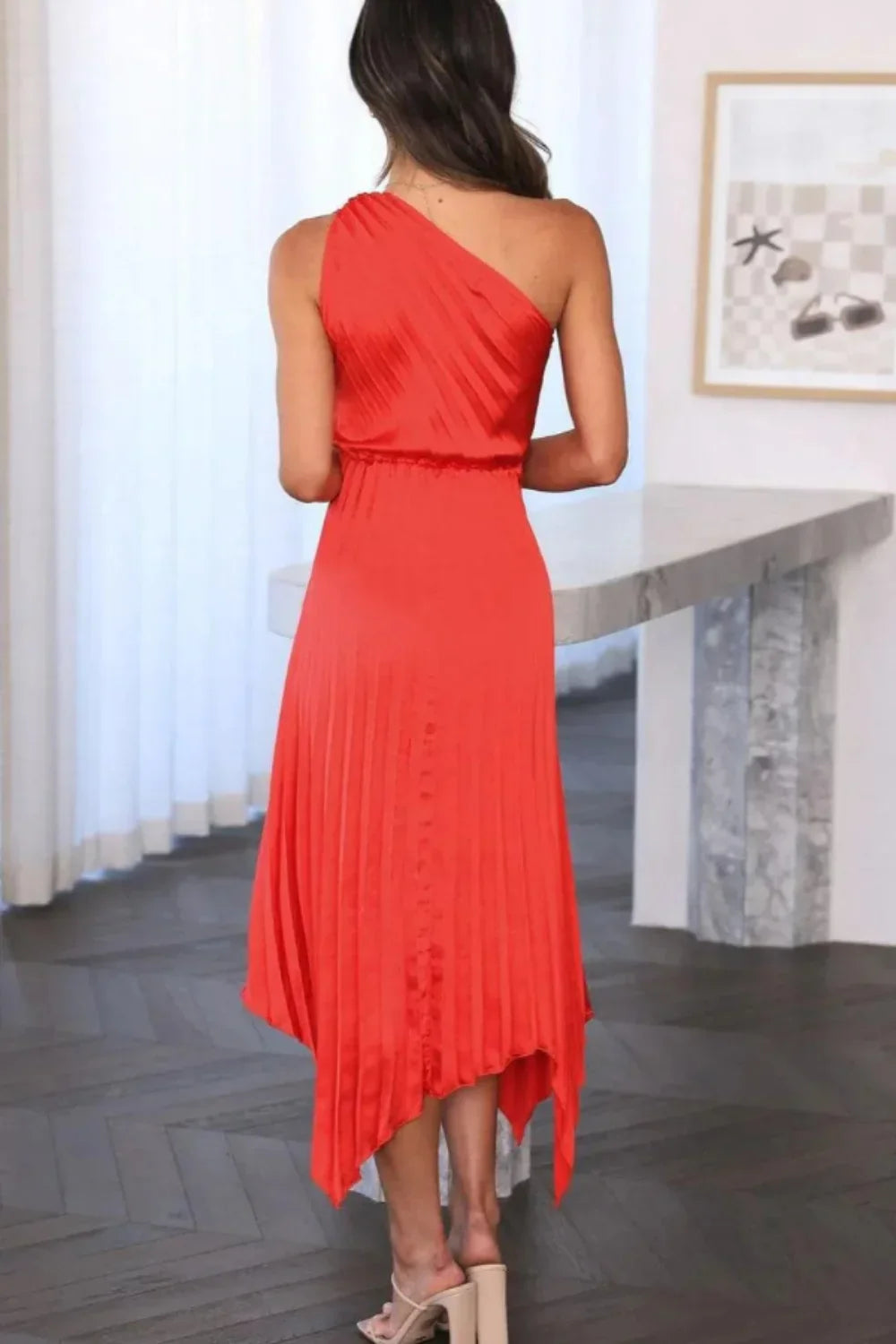 Back view of the Kouvr Fashion red one-shoulder dress showing elasticated waist" or "Side detail of the asymmetrical pleated hem on the Kouvr Fashion cocktail dress