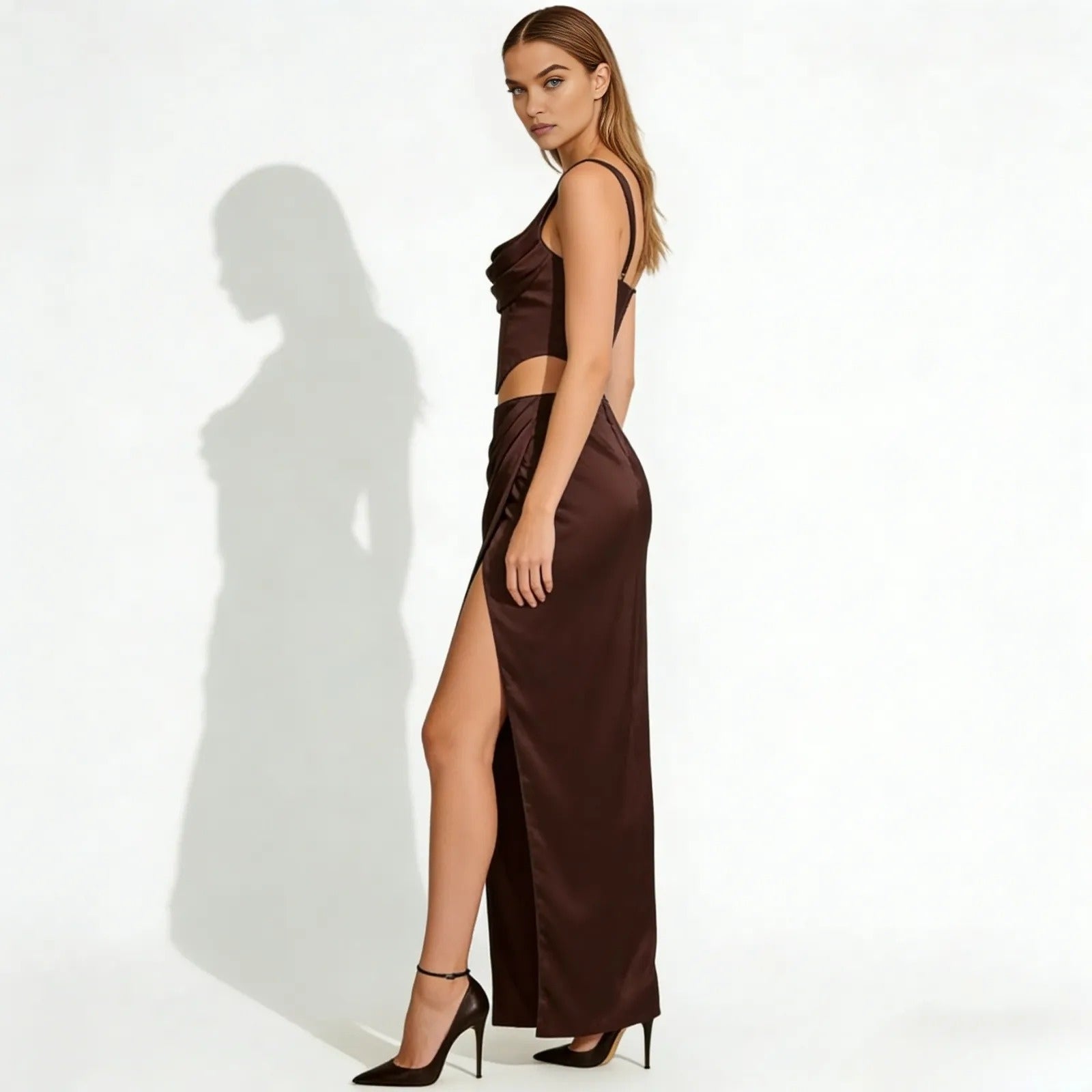 Side profile of a model in the Rona dark brown satin formal set, highlighting the high thigh slit of the maxi skirt and the fit of the corset crop top.