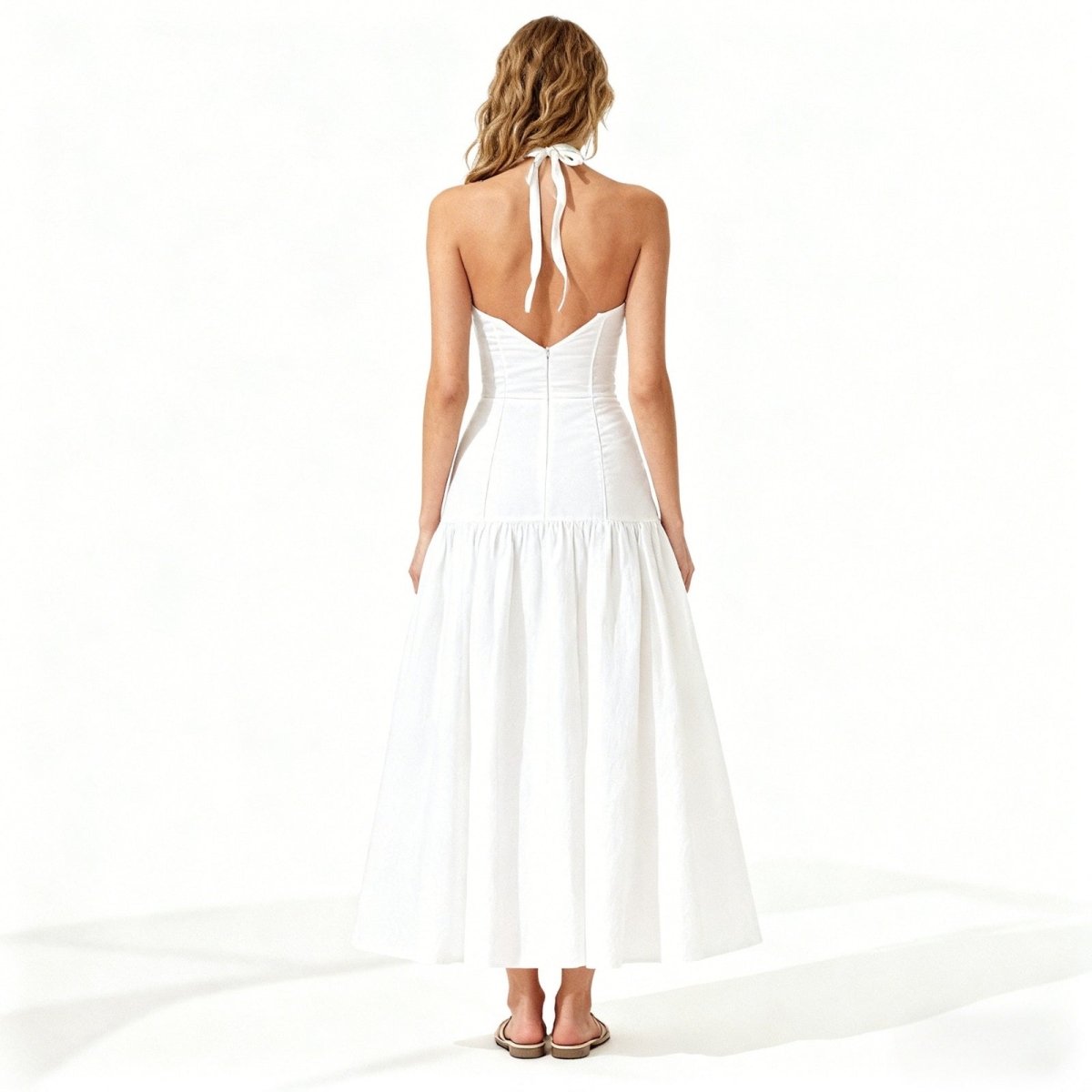 Woman wearing a white kouvr halter neck dress on a white background