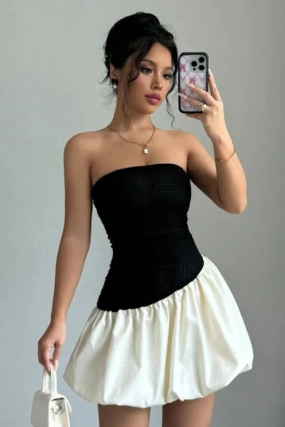 Model wearing Kouvr Fashion strapless black and white bubble hem mini dress against background