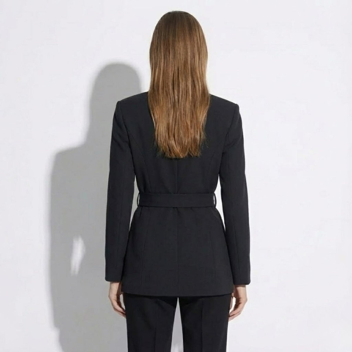 Back view of the Kouvr Fashion Gemma black blazer, highlighting the clean tailoring and belt detail across the back. 