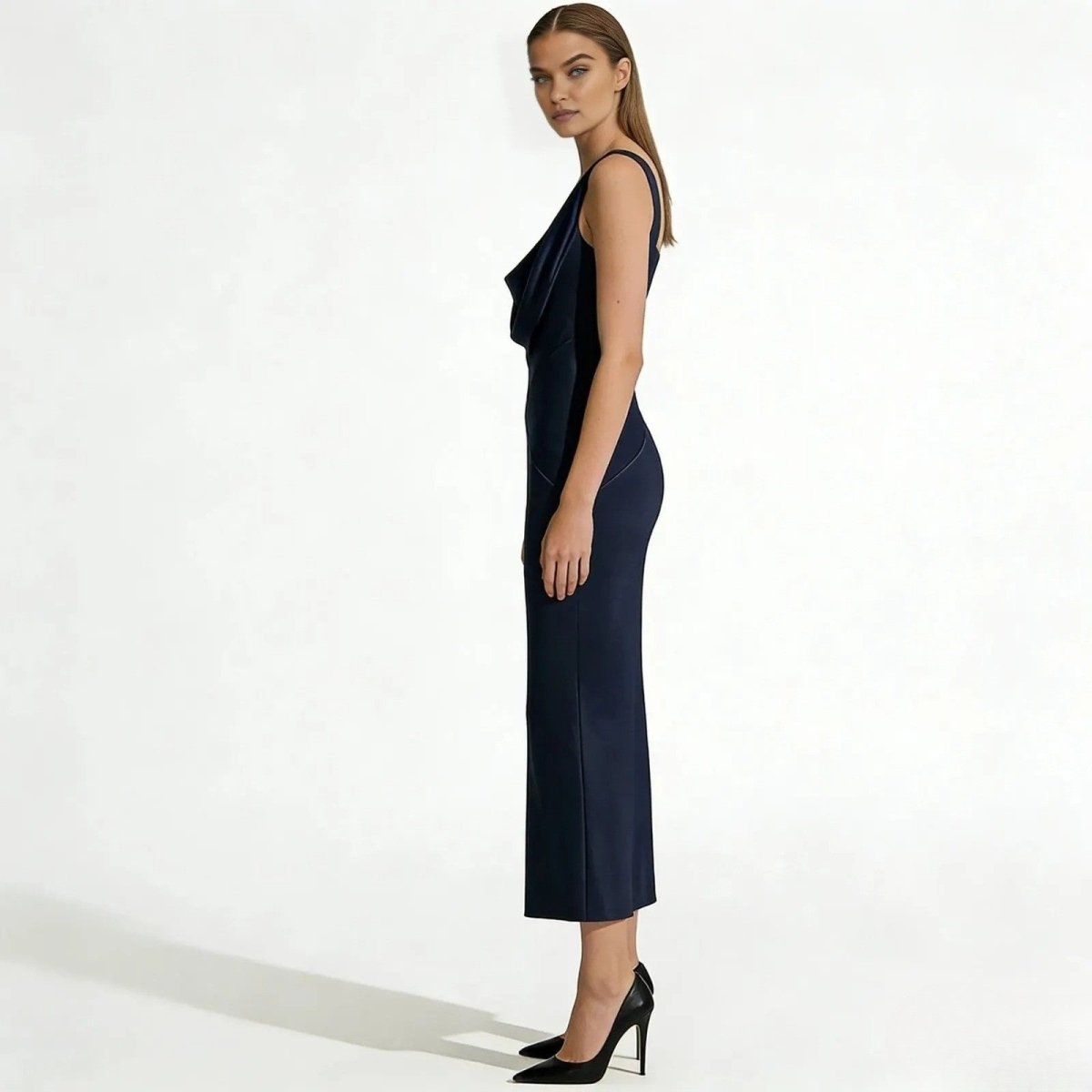 Side profile of a model in the Kouvr Fashion Vickie Gown in navy, highlighting the bias cut and form-skimming satin fabric.