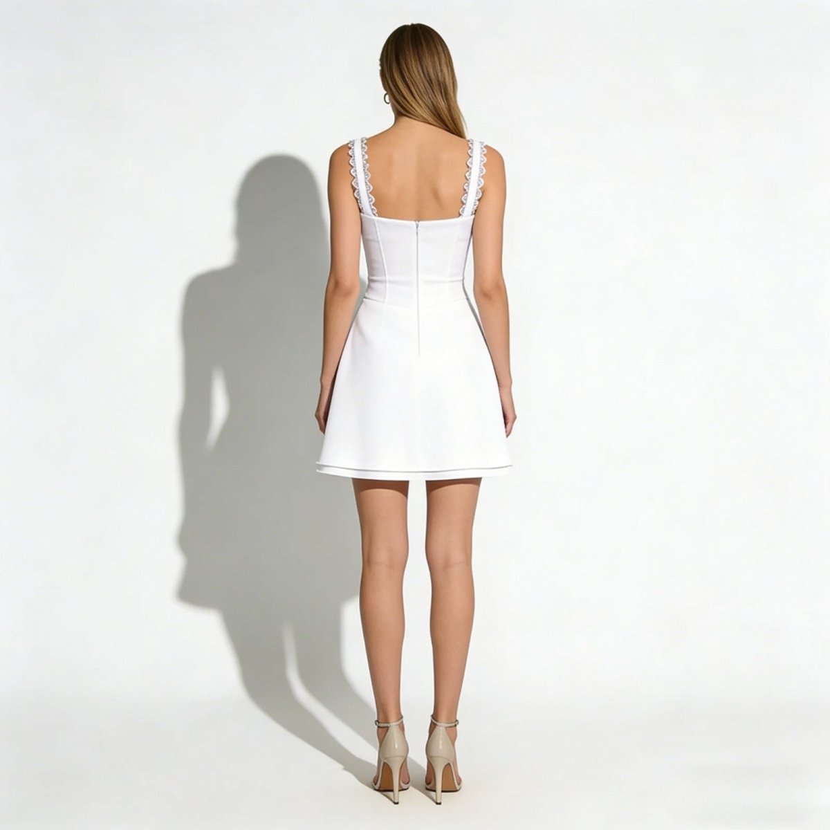 Back view of the white A-line corset mini dress showing the concealed zipper and delicate lace strap details.