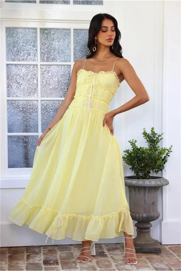 Model wearing the Kouvr Fashion Yoona Yellow Ruffle Midi Dress in a sunlit room