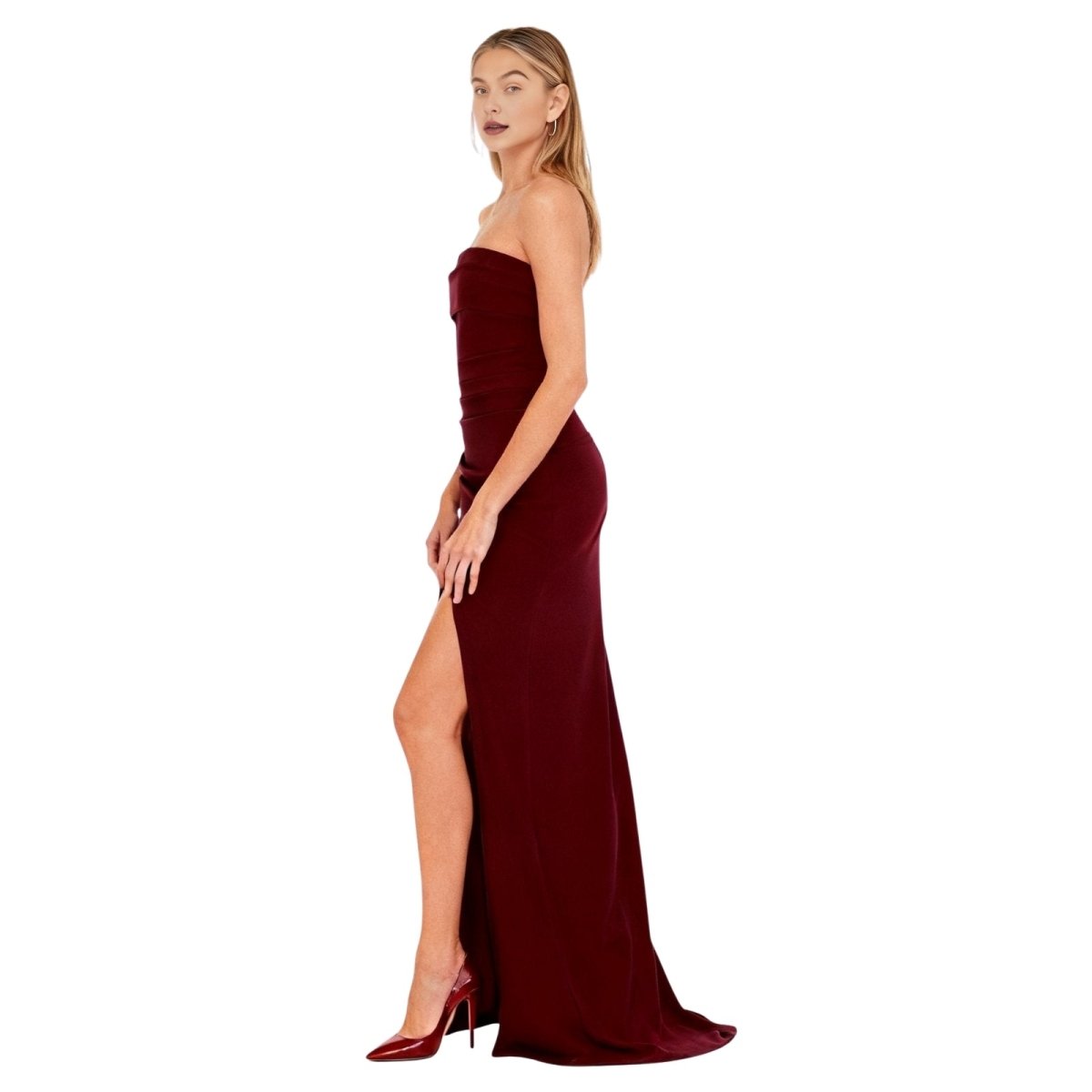 Woman wearing a burgundy kouvr strapless gown with a high slit on a white background