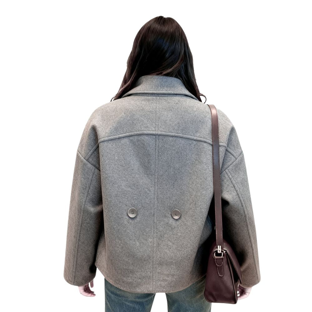 Back view of the Kouvr gray cropped wool jacket on a model, showing the clean back yoke seam and two decorative lower buttons.