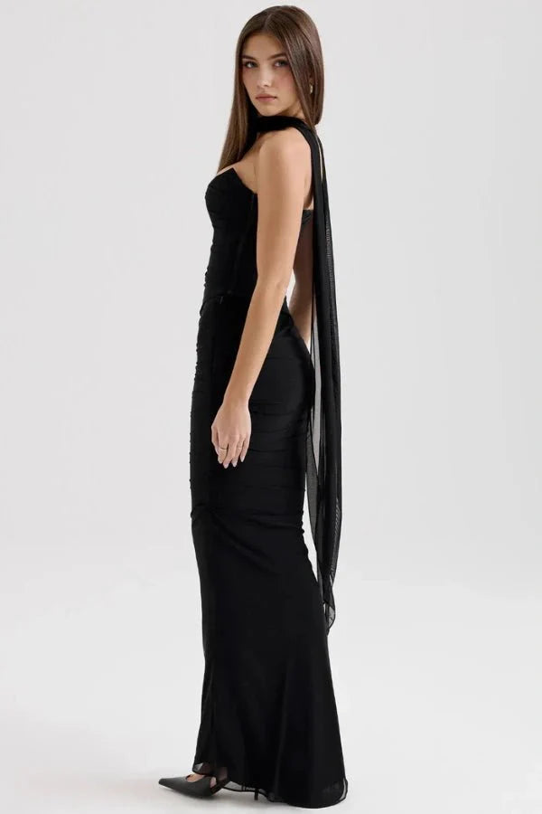 Side profile of the Kouvr Hailey black formal dress showing the fitted silhouette and an elegant, long chiffon scarf extending from the choker neckline.