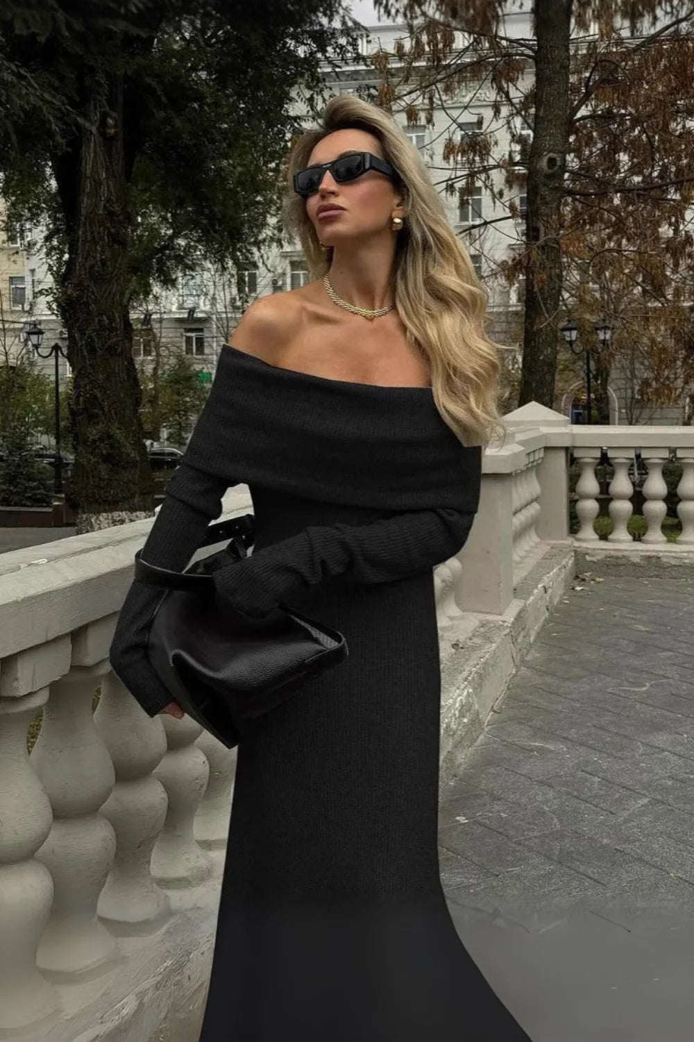 Model from behind wearing Kouvr Ingrid black ribbed knit off the shoulder maxi dress