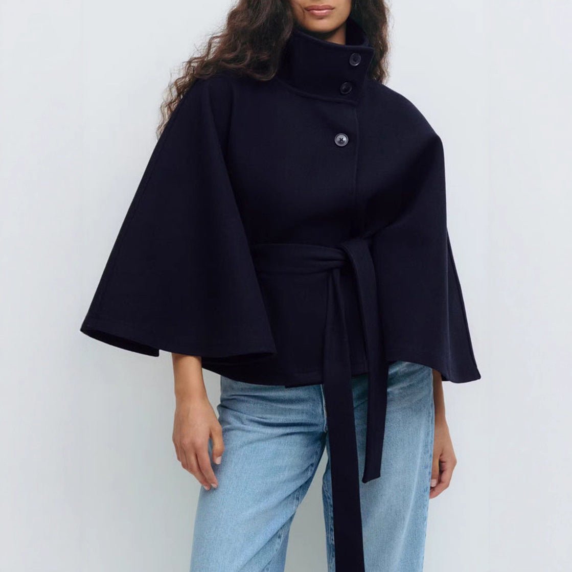 Model wearing the Kouvr Jannah Funnel Neck Wool Cape in Midnight Navy, belted at the waist and paired with light-wash denim