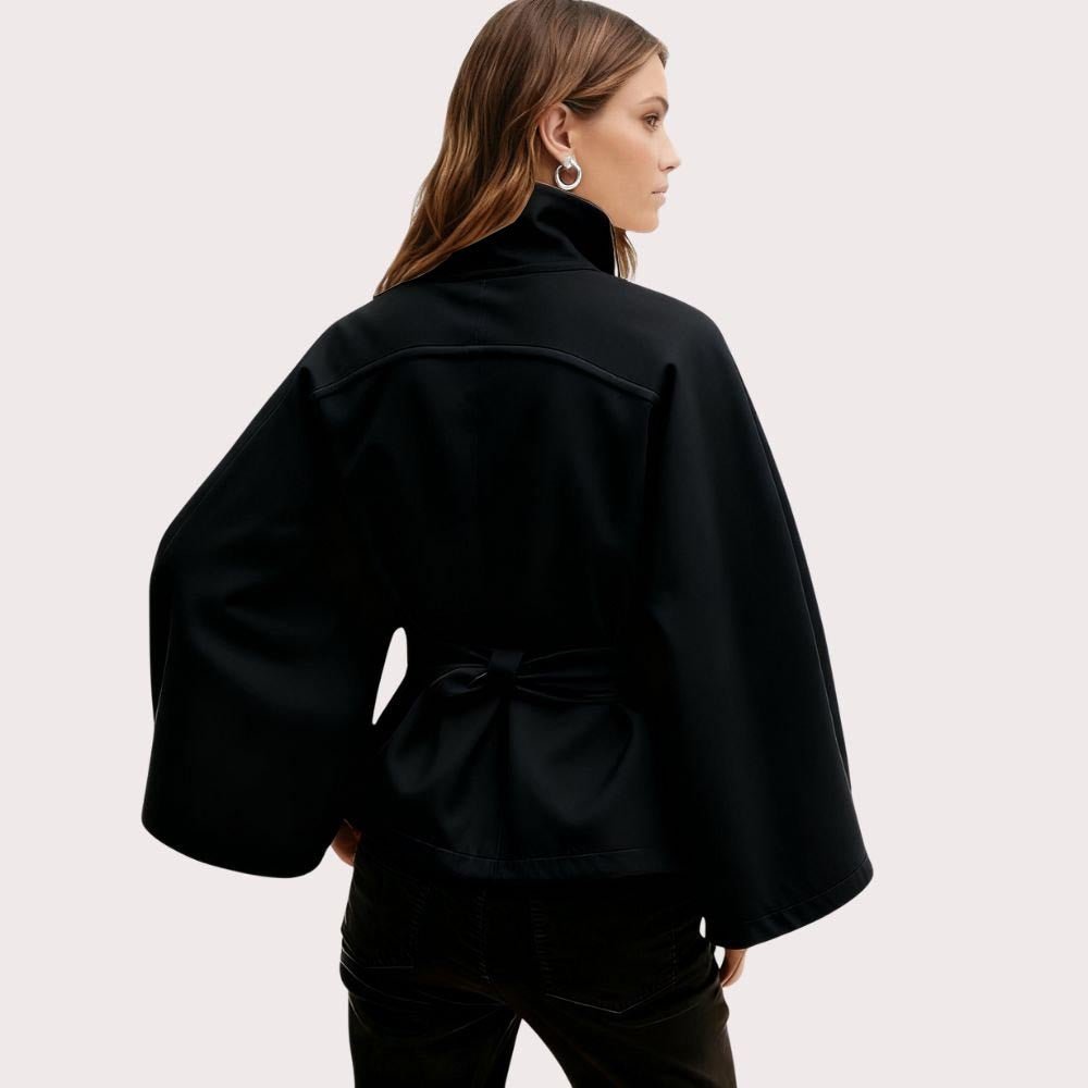 Model from behind wearing the black Kouvr Jaye Cape Jacket, showcasing the tie-back belt and wide kimono sleeves