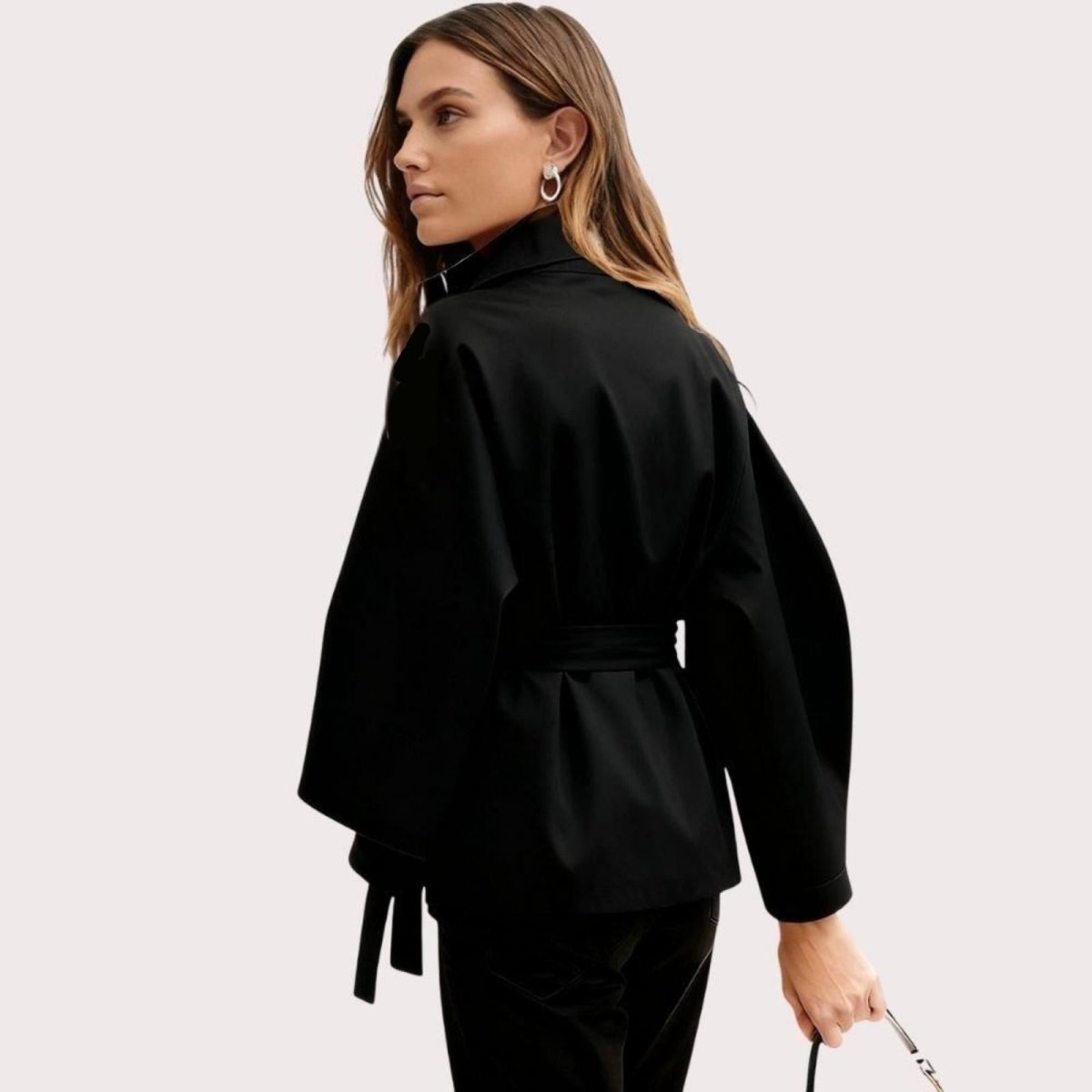 Model from side wearing the black Kouvr Jaye Cape Jacket, showcasing the tie-back belt and wide kimono sleeves
