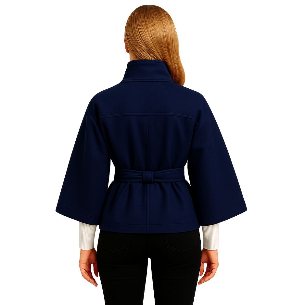 Woman wearing the Kouvr Jaye Cape in navy blue, featuring a high funnel neck, wide sleeves, and a self-tie belt