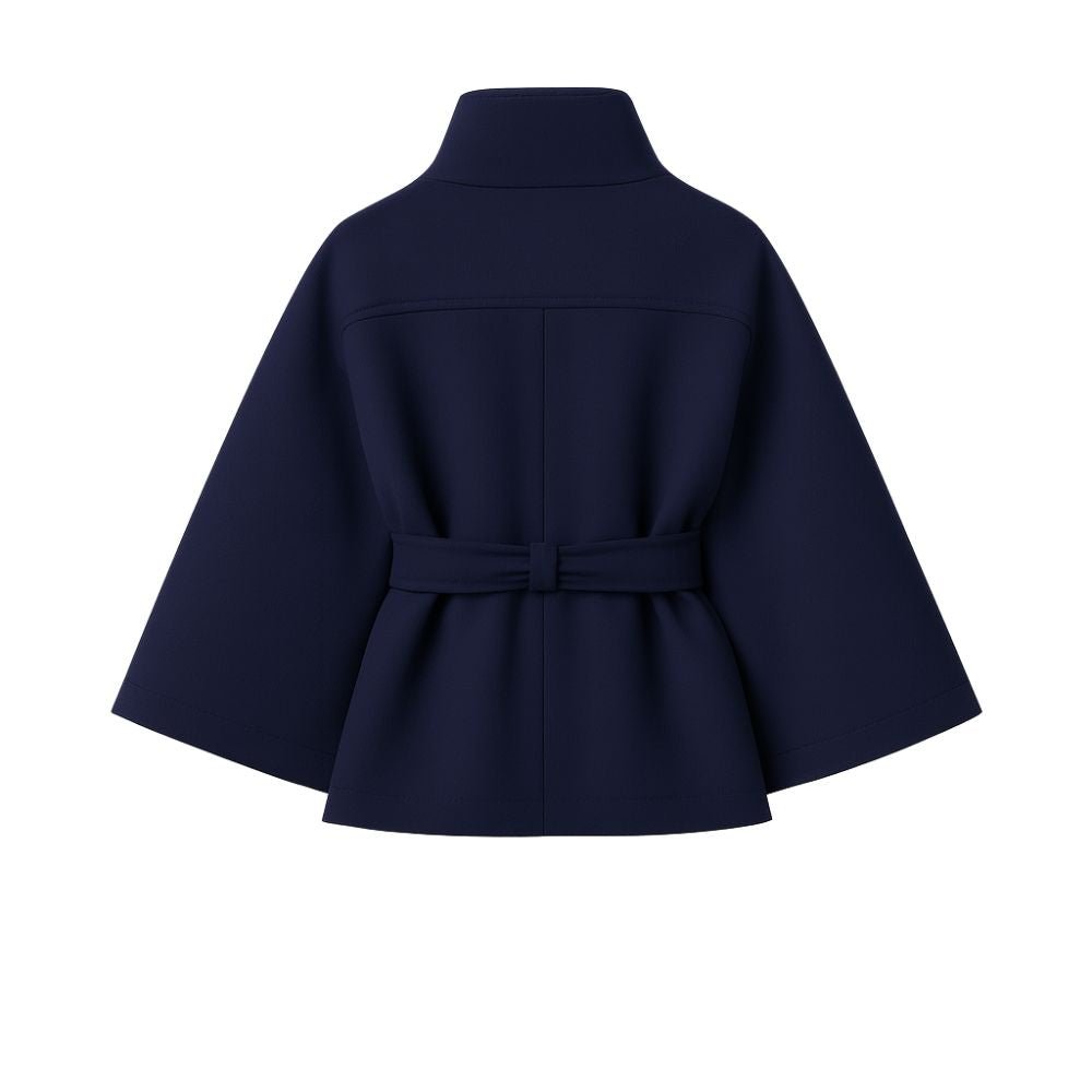 Woman wearing the Kouvr Jaye Cape in navy blue, featuring a high funnel neck, wide sleeves, and a self-tie belt