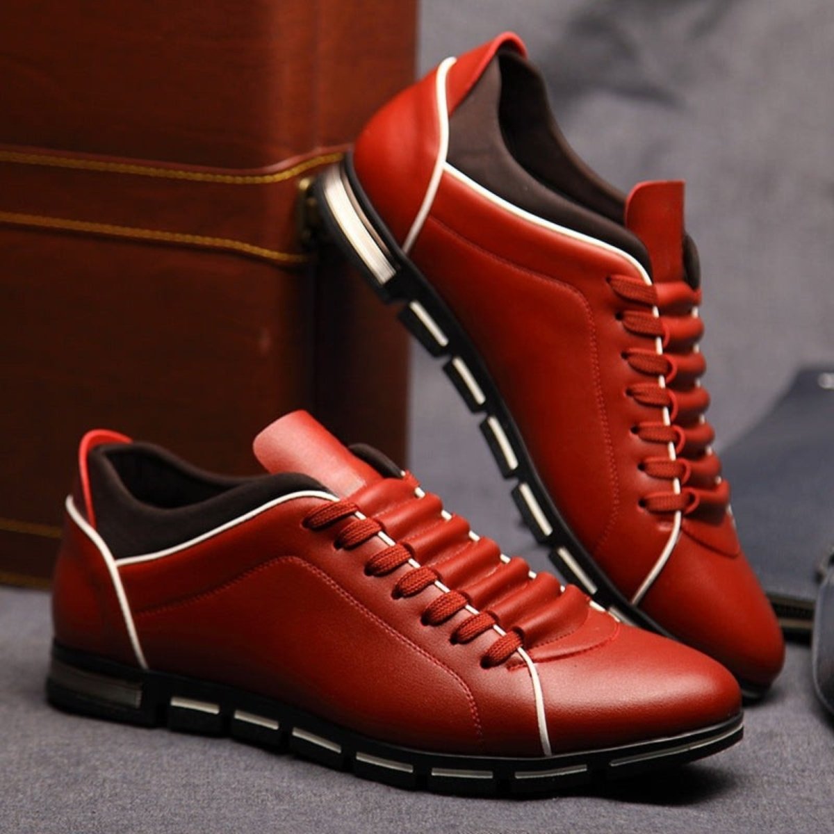 A pair of rich red leather Kouvr Jimmy men's smart casual shoes with distinctive white trim and a modern black sole.

