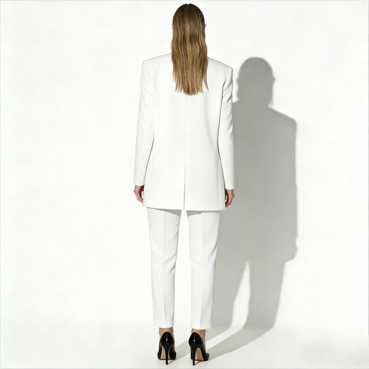 Back view of the Kouvr Kate women's white suit, highlighting the clean lines, center vent on the blazer, and expert tailoring from behind.
