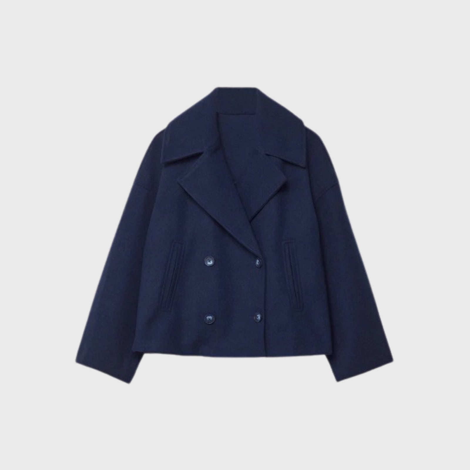 Studio flatlay of the Kouvr Katherine navy cropped wool peacoat, detailing the wide lapels and double-breasted corozo button closure.