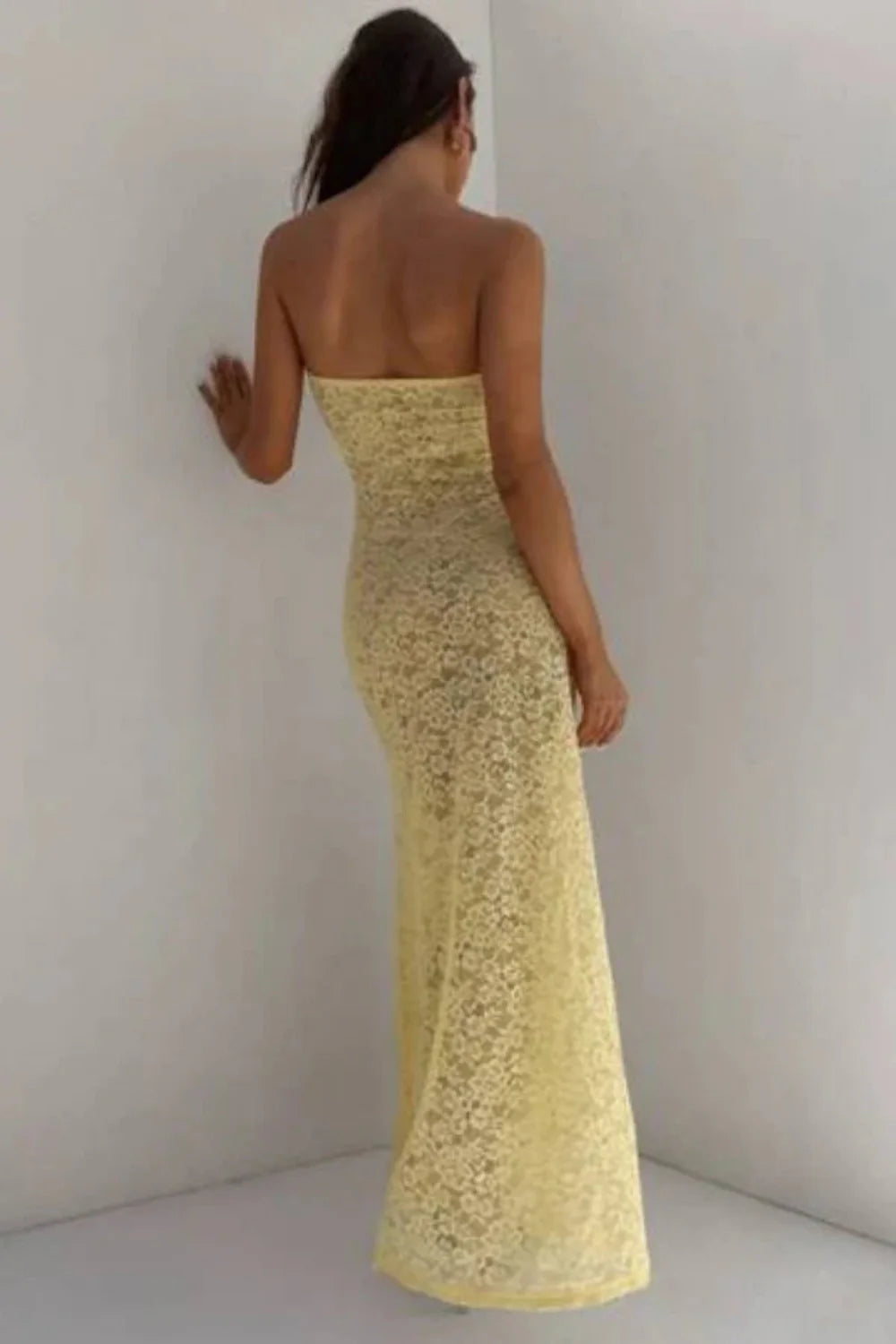 Model wearing the Kouvr Mariposa strapless lace floor-length dress in Buttercup Yellow against a white wall