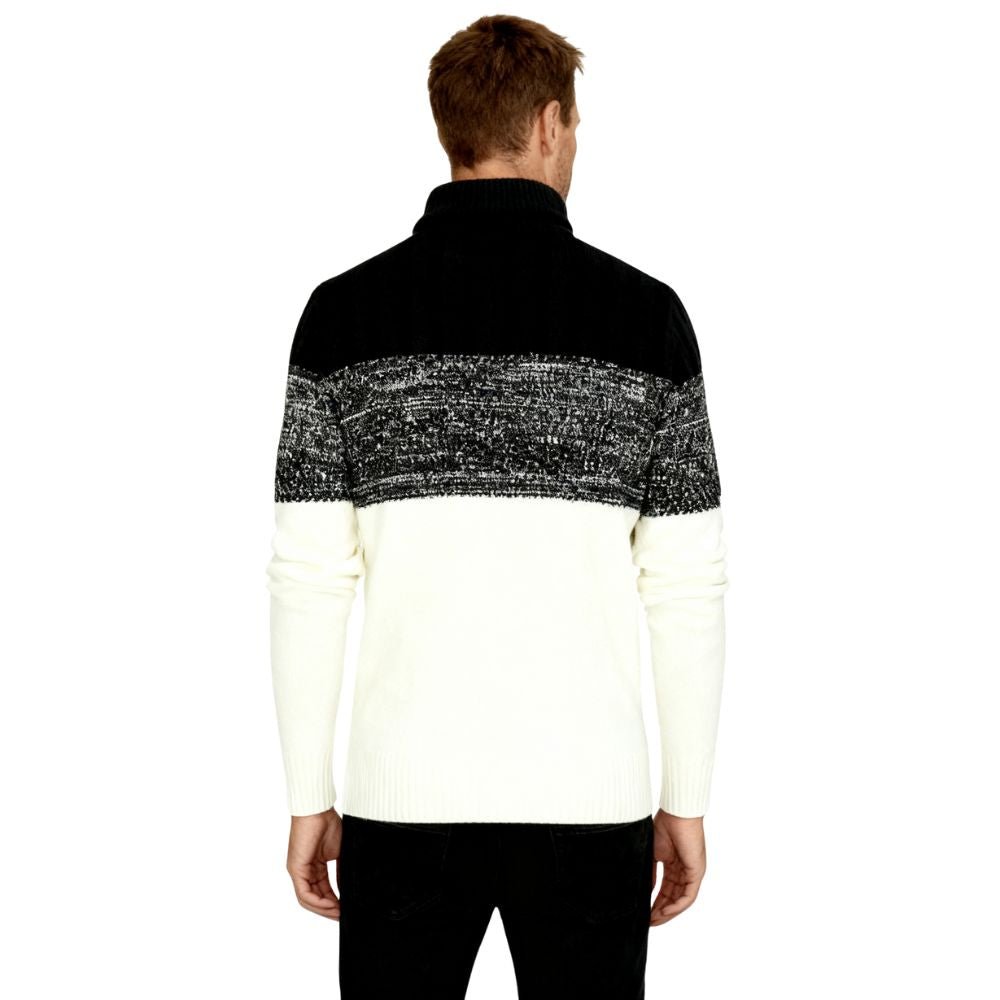 A man wearing the Kouvr color block turtleneck sweater in black, textured grey, and cream, paired with black trousers.