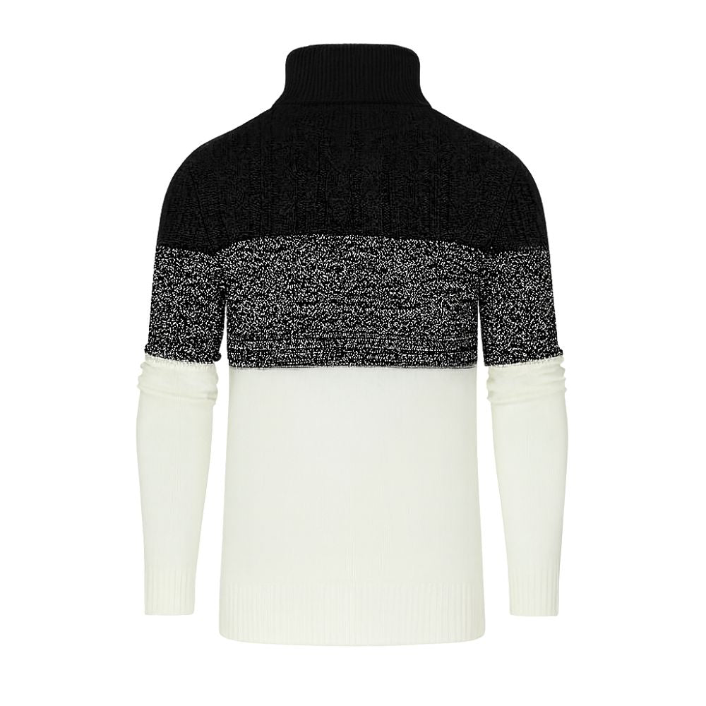 A man wearing the Kouvr color block turtleneck sweater in black, textured grey, and cream, paired with black trousers.