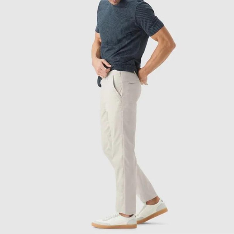 Side profile of a man wearing Kouvr All-Day Commuter Pants in khaki with a navy polo shirt, highlighting the slim fit and modern silhouette.