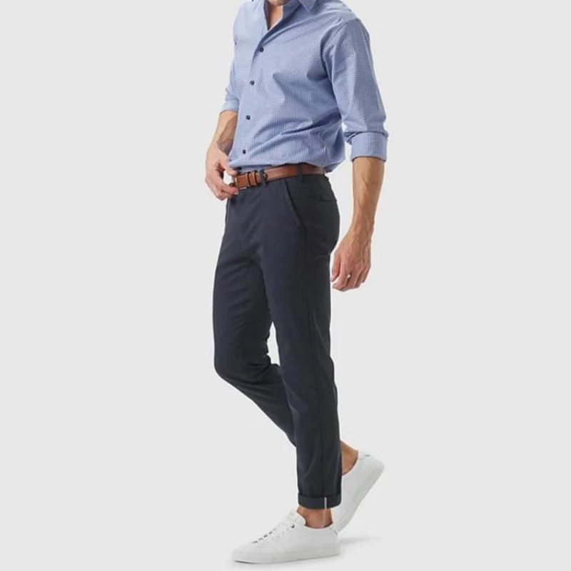 Man wearing Kouvr All-Day Commuter Pants in navy with a light blue patterned dress shirt and a brown belt, showcasing their office-ready versatility.
