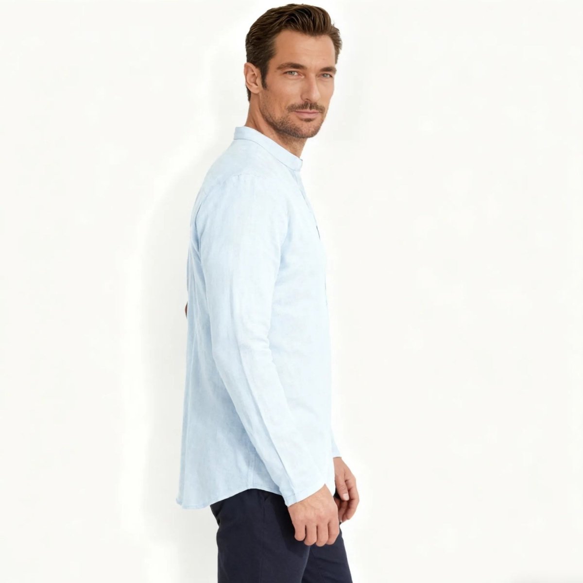 Side profile of a man in a light blue grandad collar linen shirt from Kouvr Fashion, showcasing the sleeve and drape of the fabric.
