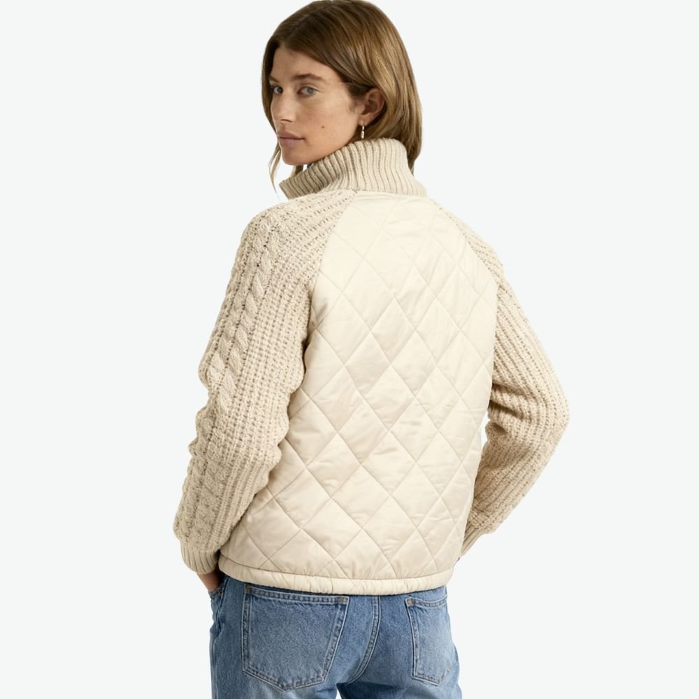 Woman wearing the Kouvr Mika khaki quilted jacket with cable knit sleeves, styled with jeans