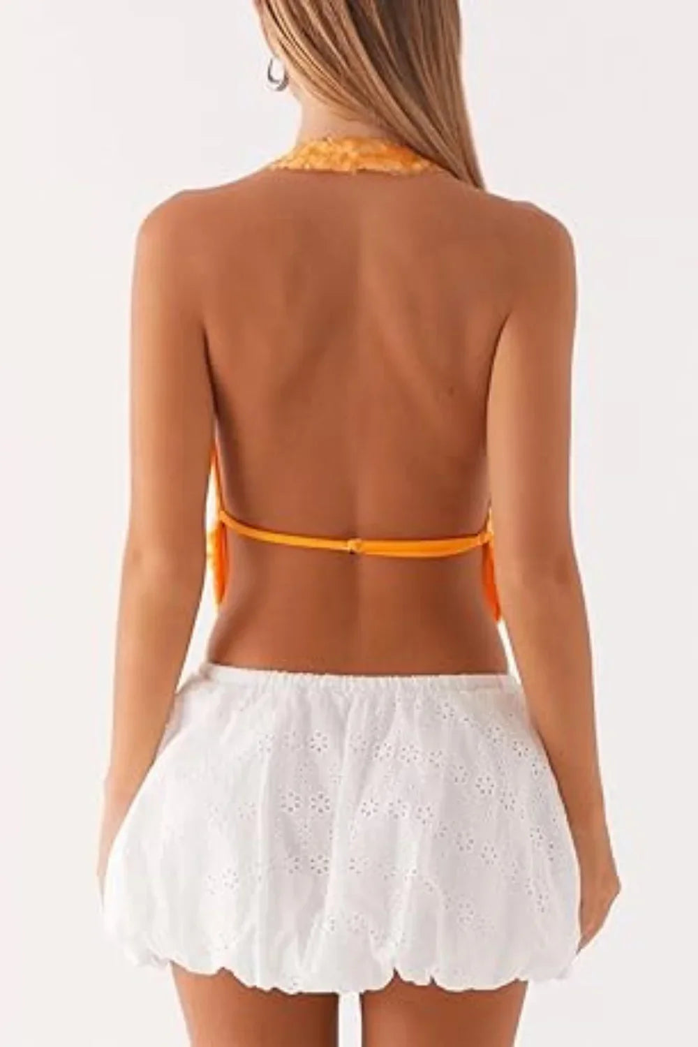 Model wearing Kouvr's Rosette featuring an orange sequin backless halter top