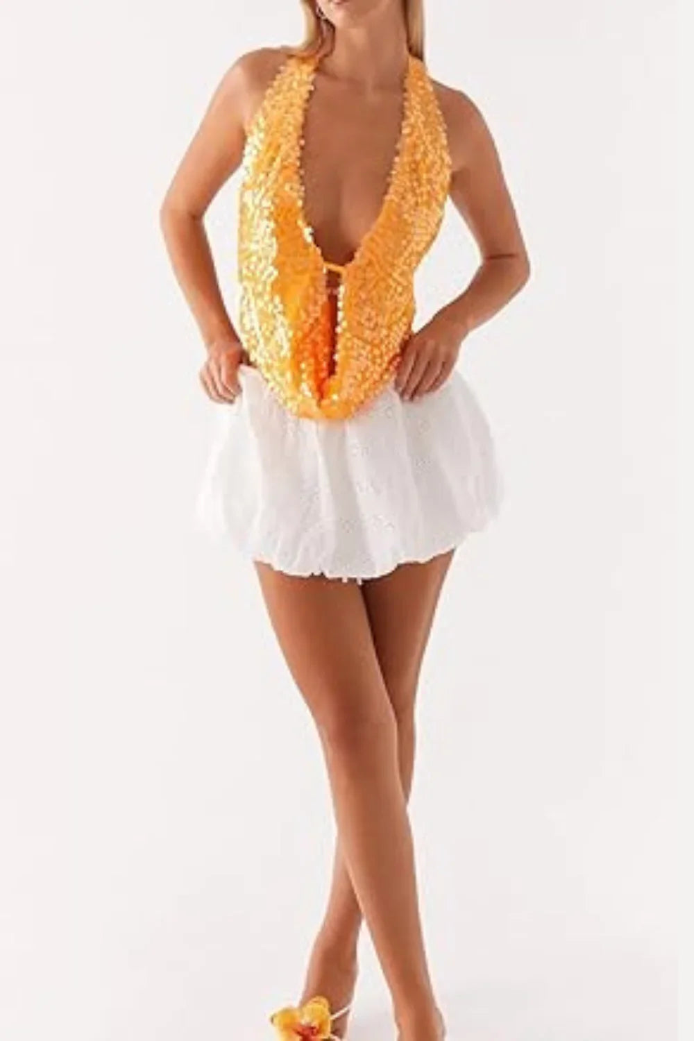 Model wearing Kouvr's Rosette featuring an orange sequin backless halter top
