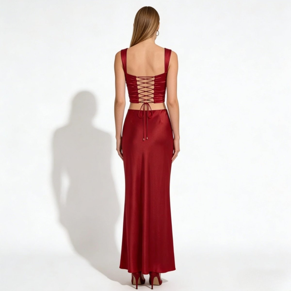 Back view of the Rona red satin crop top, detailing the adjustable corset-style lace-up design and matching high-waisted maxi skirt.