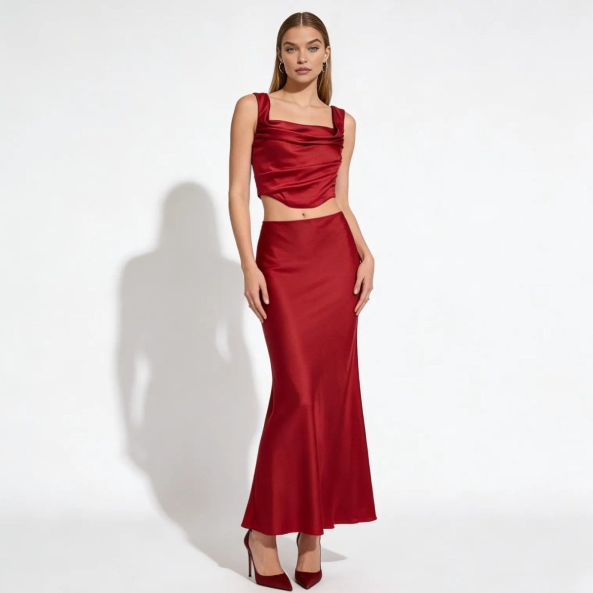 Model wearing the Rona red satin set, featuring a cowl neck crop top and matching long maxi skirt, on a white background.