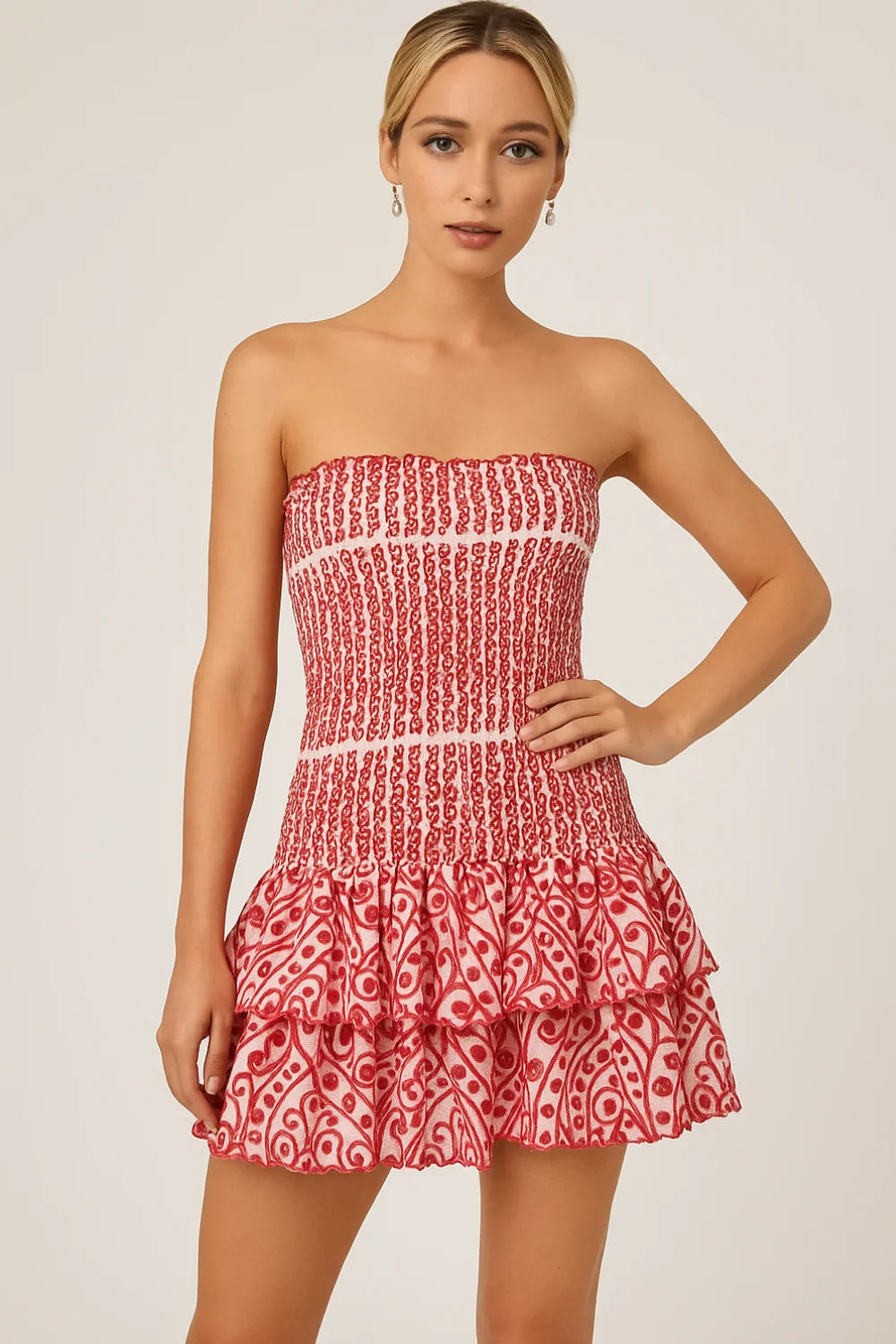 Model wearing the Kouvr red strapless mini dress with a smocked bodice and tiered ruffle skirt