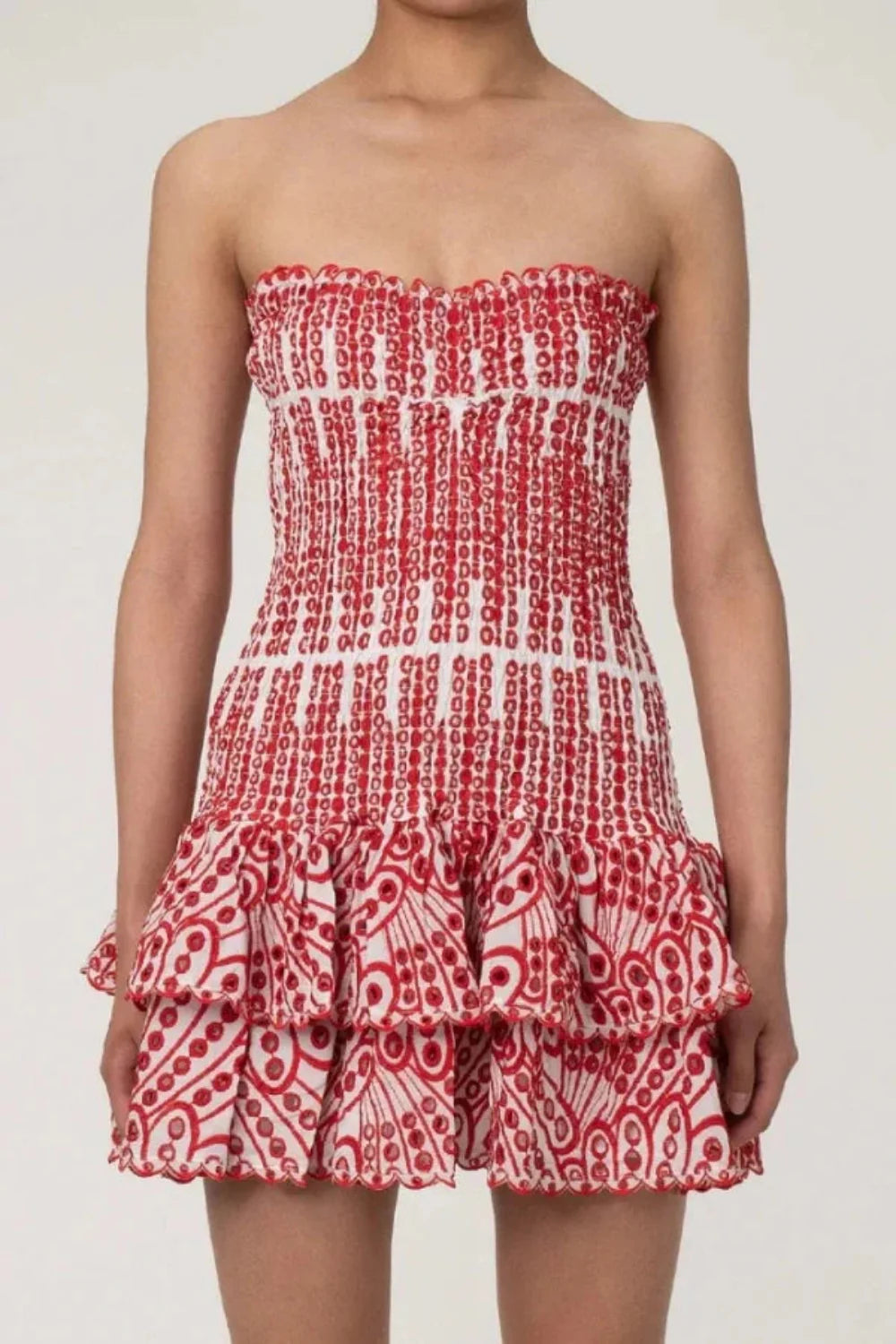 Model wearing the Kouvr red strapless mini dress with a smocked bodice and tiered ruffle skirt
