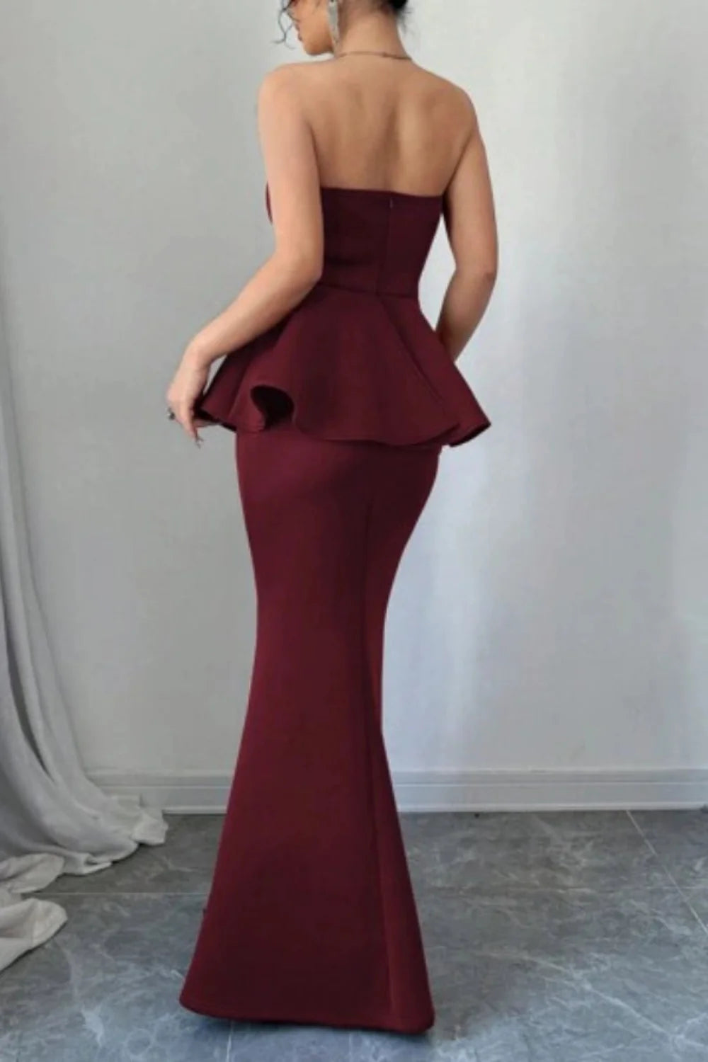 Model wearing Kouvr's burgundy strapless peplum mermaid gown for a formal event