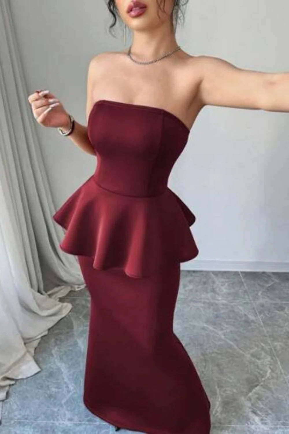 Model wearing Kouvr's burgundy strapless peplum mermaid gown for a formal event