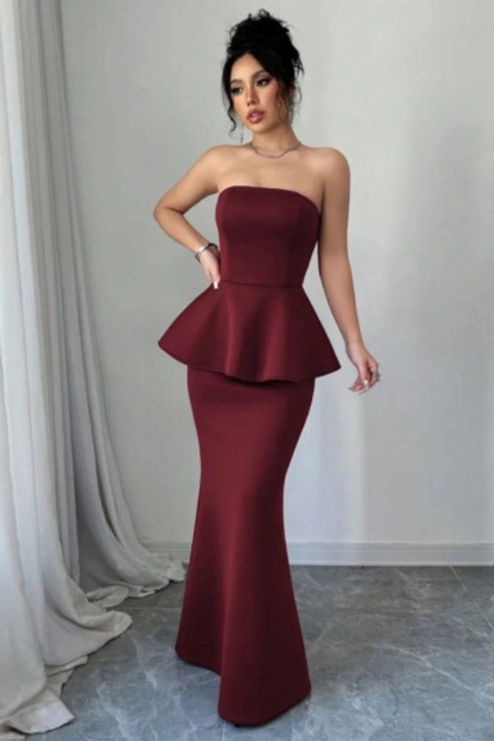 Model wearing Kouvr's burgundy strapless peplum mermaid gown for a formal event
