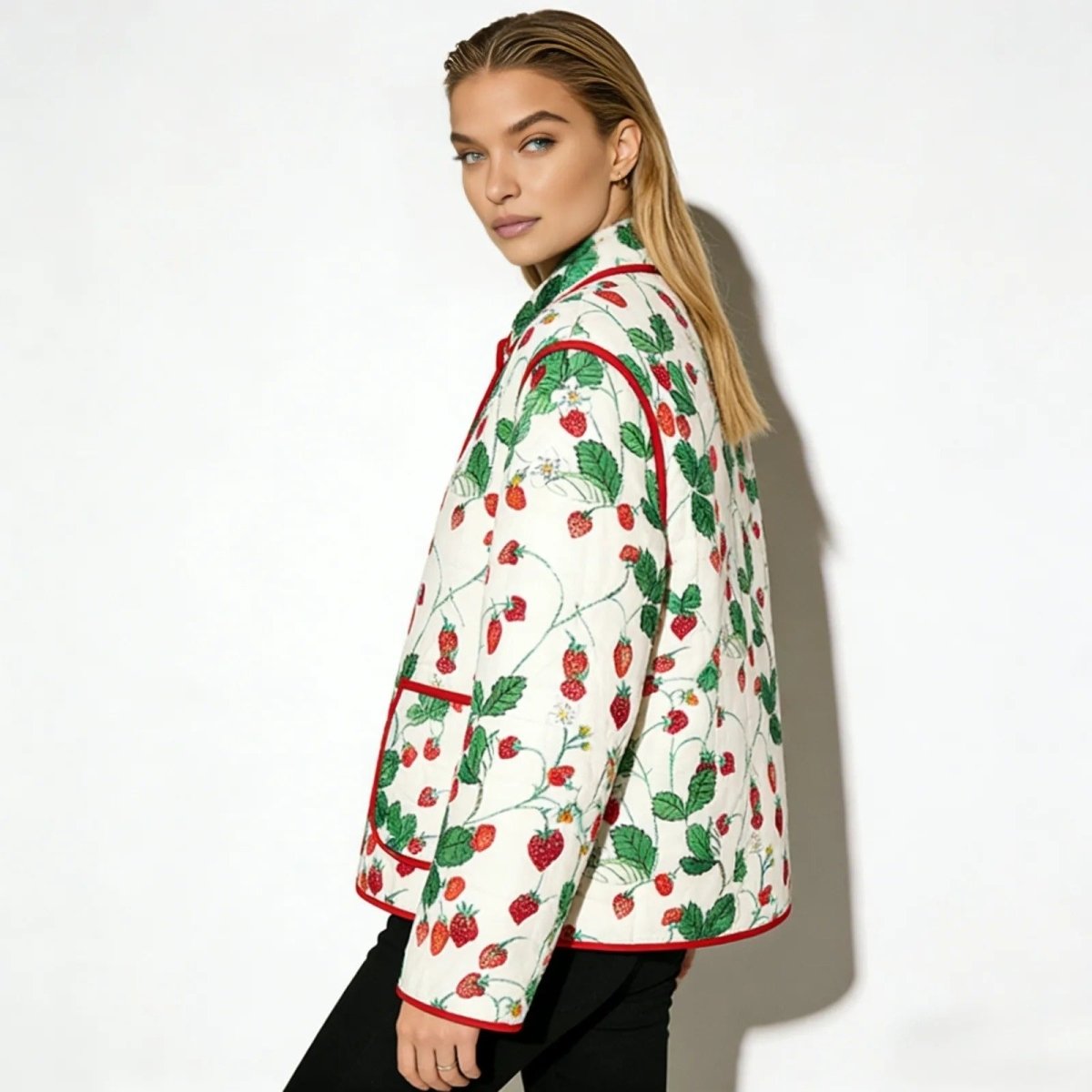 Side profile of a model wearing the white and red strawberry print Kouvr quilted jacket, showcasing its fit and sleeve detail.