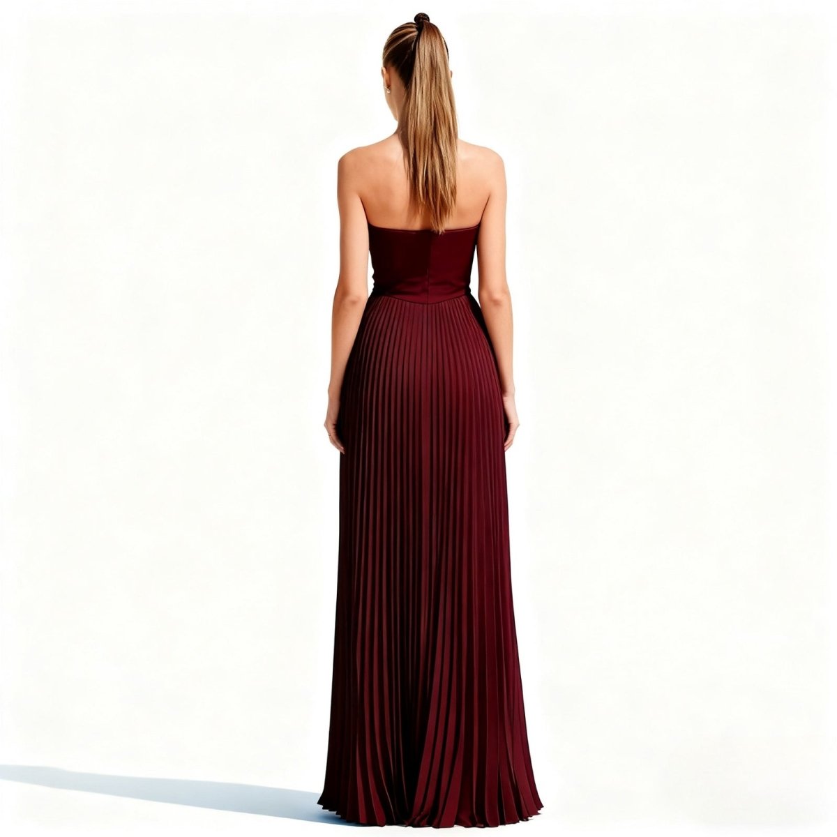 Woman wearing a burgundy kouvr strapless gown on a white background