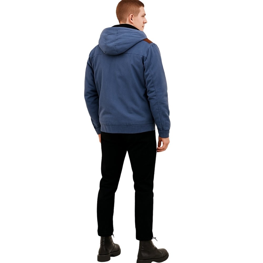 Man wearing the Kouvr tyrian sherpa-lined blue canvas hooded jacket, facing back with hands in pockets.