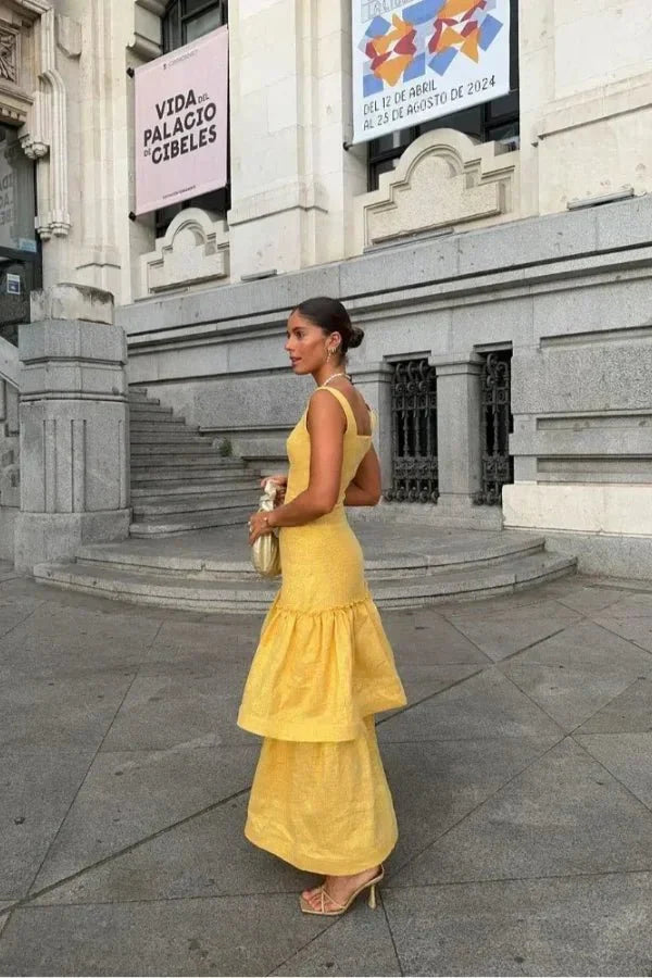 Model wearing the Kouvr Valeria canary yellow tiered ruffle maxi dress at an outdoor event