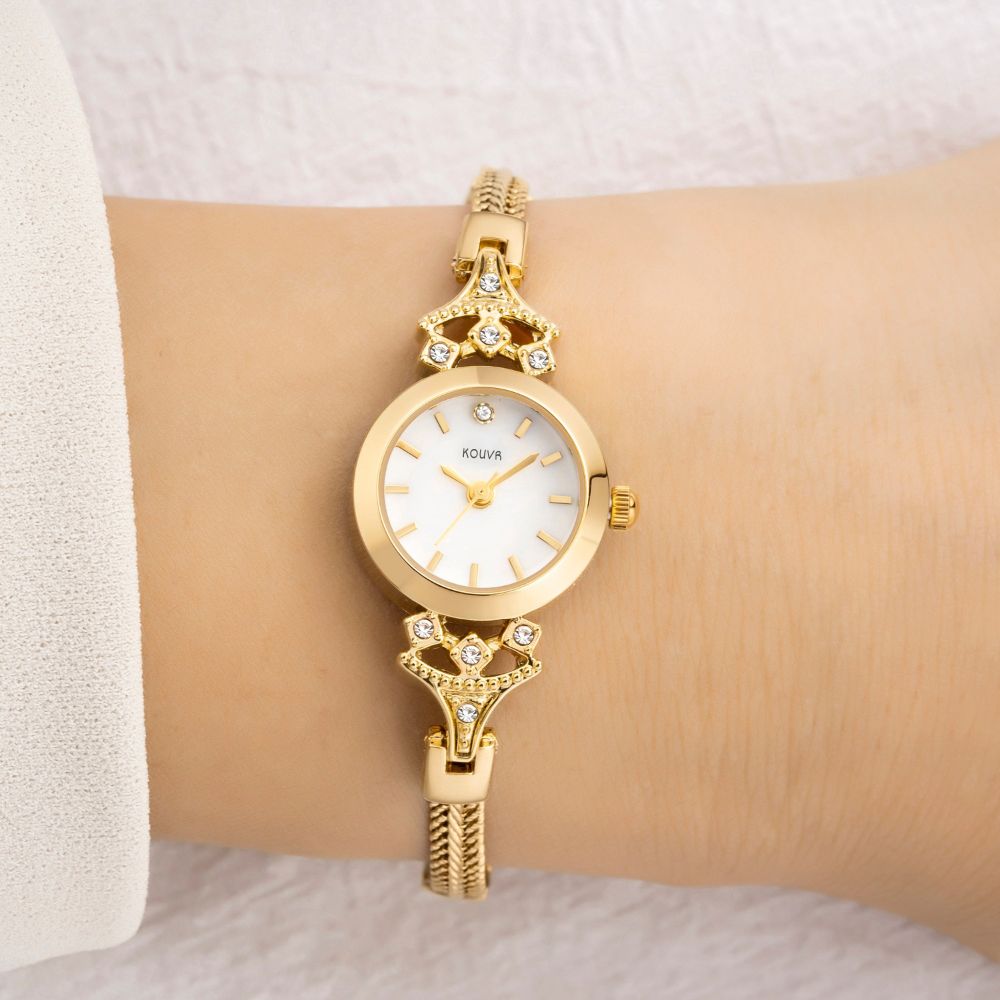 Gold kouvr wristwatch with diamond accents on a wrist against a neutral background