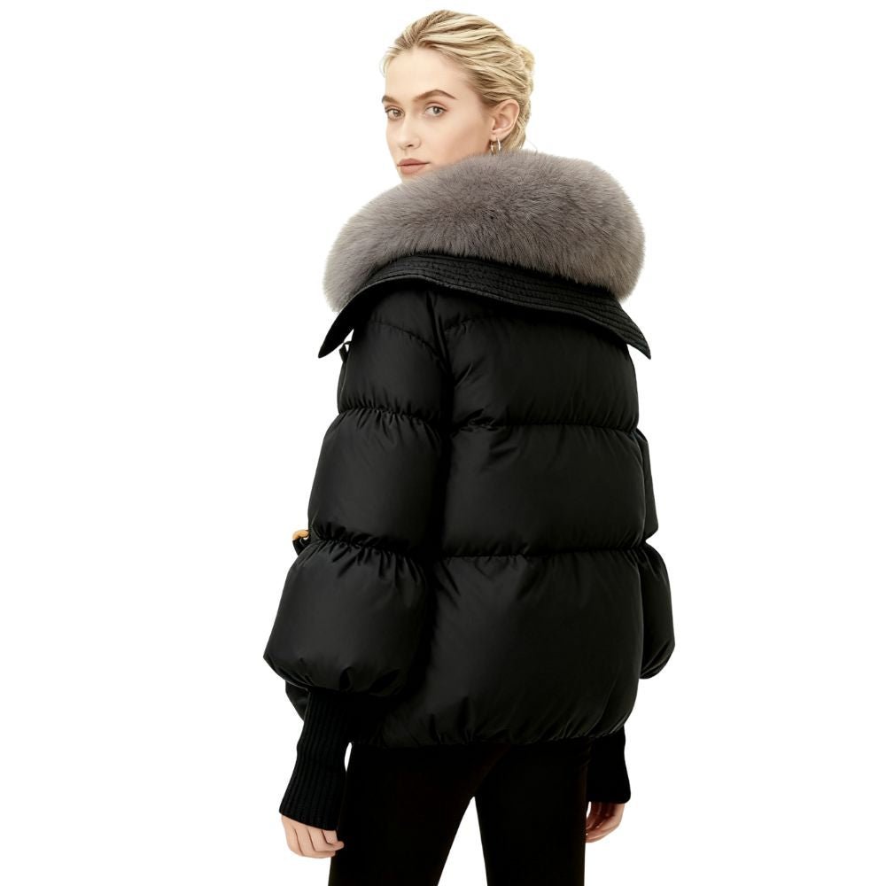 Black kouvr puffer coat with fur hood worn by a person on a white background